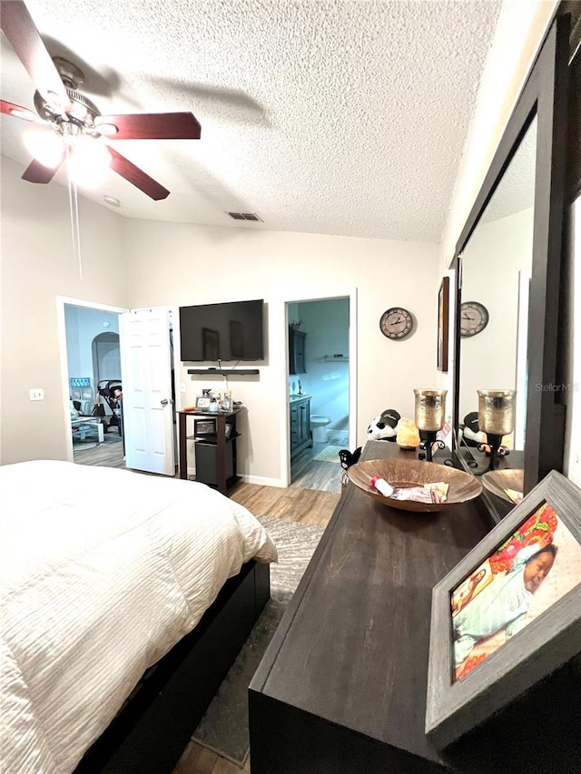 bedroom featuring vaulted ceiling, a textured ceiling, light wood-style floors, visible vents, and ceiling fan
