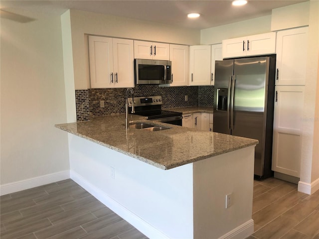 kitchen featuring white cabinets, kitchen peninsula, appliances with stainless steel finishes, and stone countertops