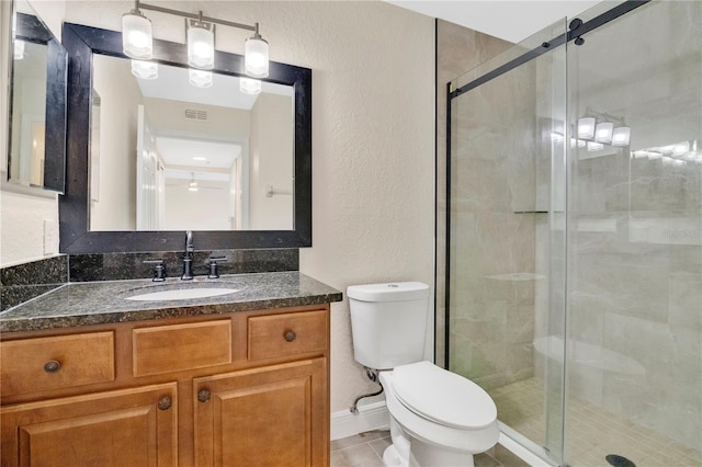 bathroom featuring tile patterned floors, vanity, toilet, and a shower with shower door