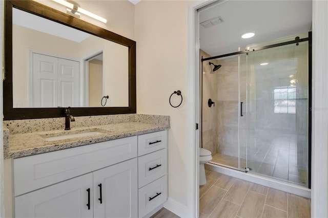 bathroom with walk in shower, vanity, and toilet