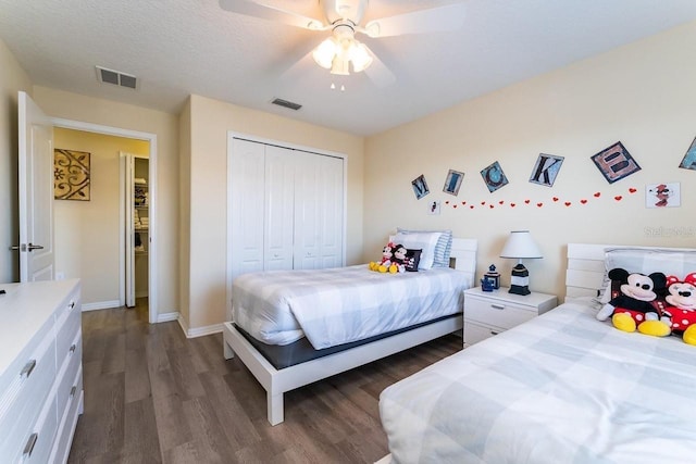 bedroom featuring a closet, dark hardwood / wood-style floors, ceiling fan, and a textured ceiling