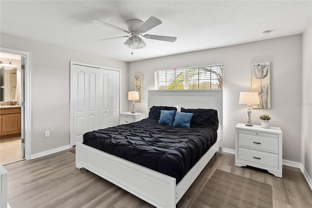 bedroom with light wood-type flooring, a textured ceiling, baseboards, and a closet