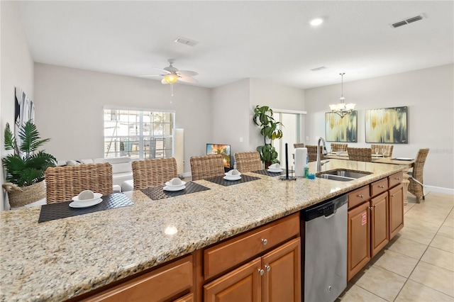 kitchen featuring visible vents, brown cabinetry, light stone countertops, stainless steel dishwasher, and a sink