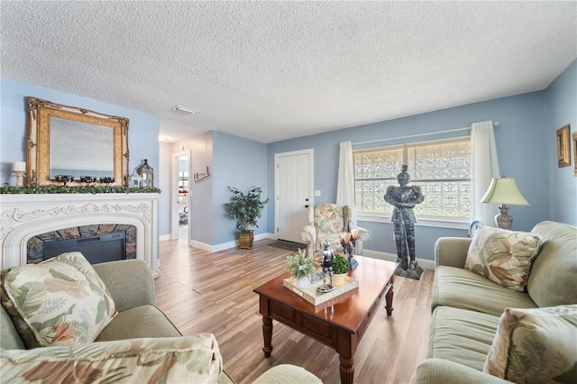 living room with light hardwood / wood-style floors, a textured ceiling, and a fireplace