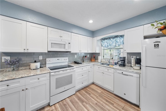 kitchen with light hardwood / wood-style floors, white appliances, and white cabinets