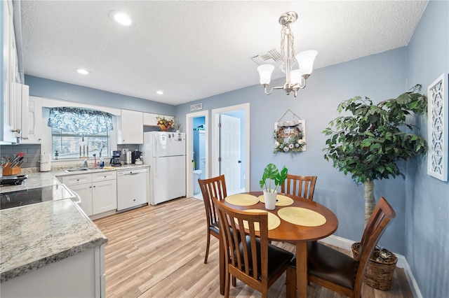 kitchen with white cabinetry, white appliances, light hardwood / wood-style flooring, decorative light fixtures, and a chandelier