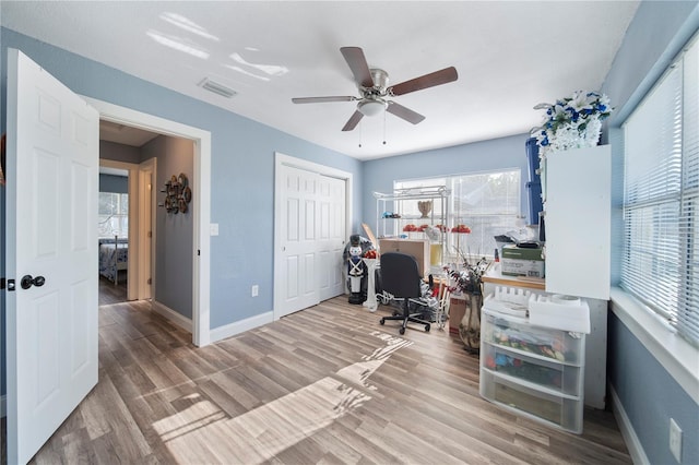 office with light wood-type flooring and ceiling fan