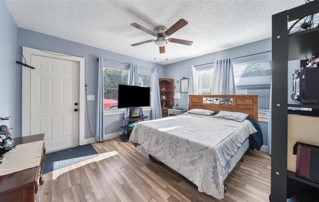 bedroom featuring light hardwood / wood-style flooring, ceiling fan, and a textured ceiling