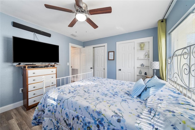 bedroom with ceiling fan, two closets, and dark wood-type flooring