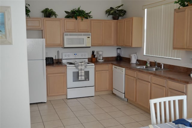 kitchen with white appliances, light brown cabinetry, and sink