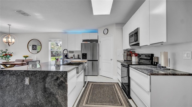 kitchen with white cabinets, hanging light fixtures, a kitchen island with sink, stainless steel appliances, and a notable chandelier