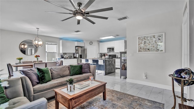 living room featuring ceiling fan with notable chandelier and sink