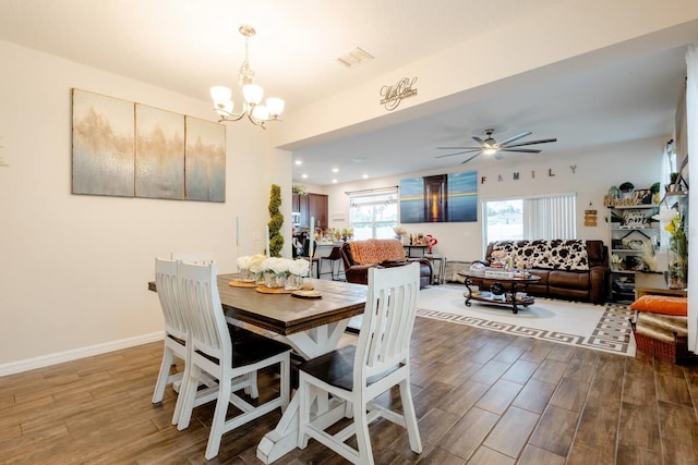 dining area with ceiling fan with notable chandelier and wood-type flooring