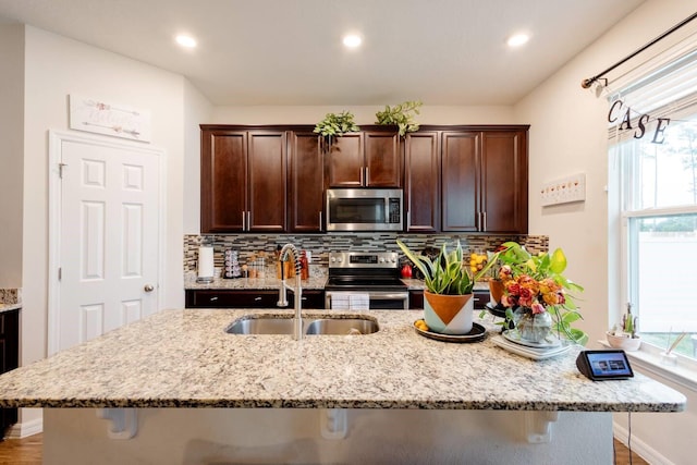 kitchen featuring a breakfast bar area, sink, backsplash, and appliances with stainless steel finishes