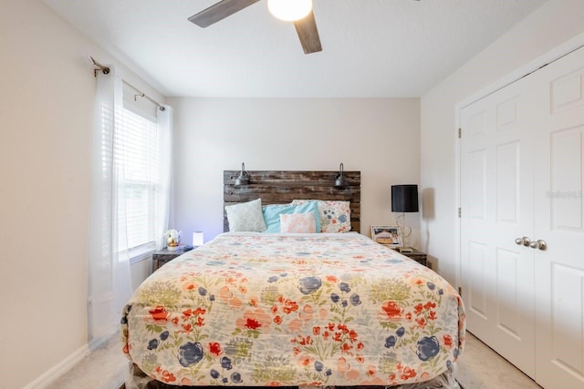 bedroom featuring a closet, multiple windows, light carpet, and ceiling fan