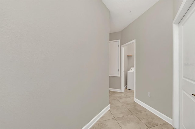 hall with washer / clothes dryer and light tile patterned floors