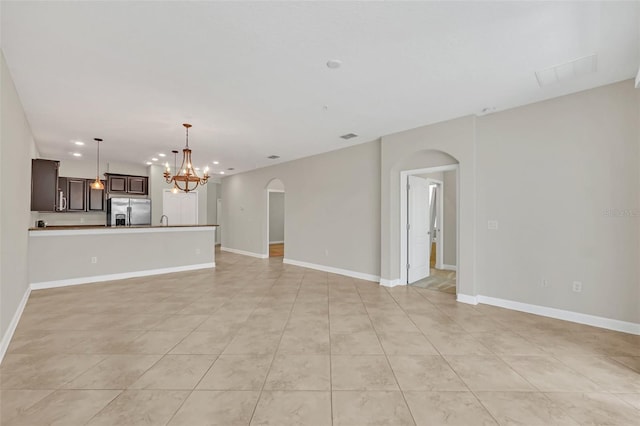 unfurnished living room with an inviting chandelier and light tile patterned floors