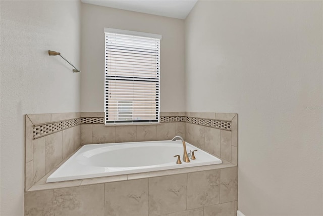 bathroom featuring a wealth of natural light and tiled tub