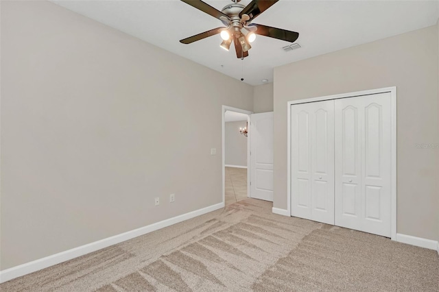 unfurnished bedroom with ceiling fan, light colored carpet, and a closet