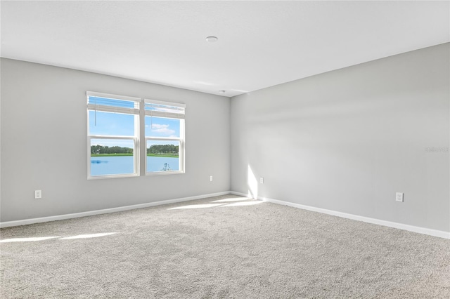 carpeted spare room featuring a water view