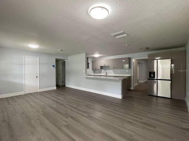 unfurnished living room with a textured ceiling, sink, and dark wood-type flooring