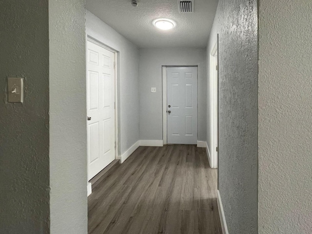 hall featuring a textured ceiling and dark hardwood / wood-style floors