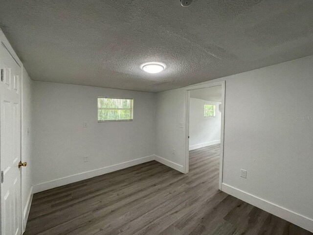 unfurnished room featuring a textured ceiling and dark hardwood / wood-style floors