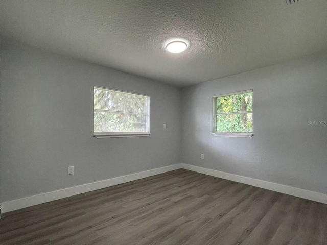 spare room featuring a textured ceiling and dark hardwood / wood-style floors