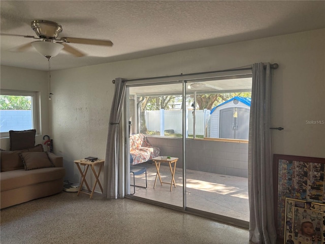 doorway with a wealth of natural light, ceiling fan, and a textured ceiling