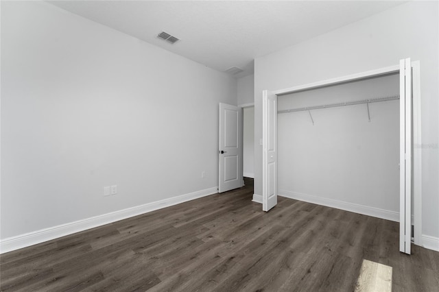 unfurnished bedroom with a closet and dark wood-type flooring