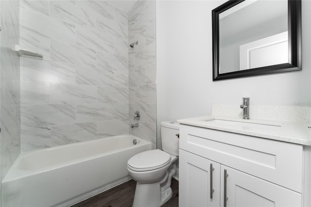 full bathroom with hardwood / wood-style flooring, tiled shower / bath combo, vanity, and toilet