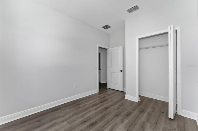 unfurnished bedroom with dark hardwood / wood-style flooring and a closet