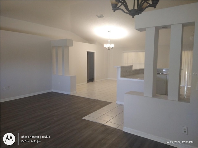 spare room featuring light wood-type flooring, vaulted ceiling, and a chandelier