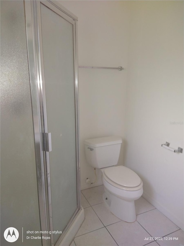 bathroom featuring tile patterned flooring, toilet, and an enclosed shower