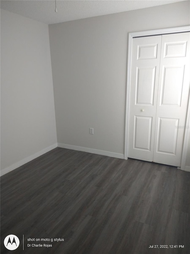 unfurnished bedroom featuring a closet, dark wood-type flooring, and a textured ceiling