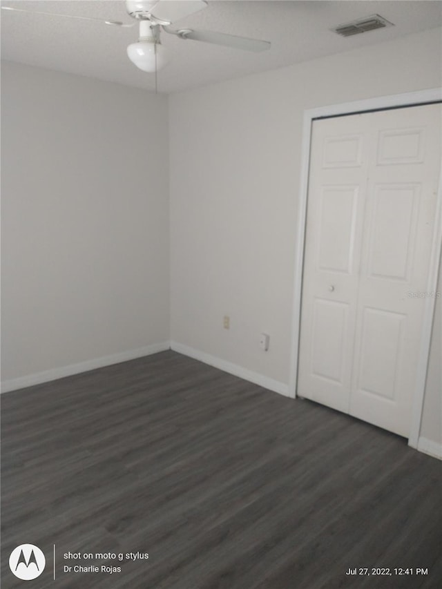 unfurnished bedroom featuring a closet, ceiling fan, and dark wood-type flooring