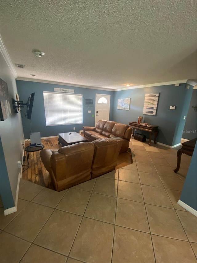 living area with tile patterned floors, a textured ceiling, visible vents, baseboards, and crown molding