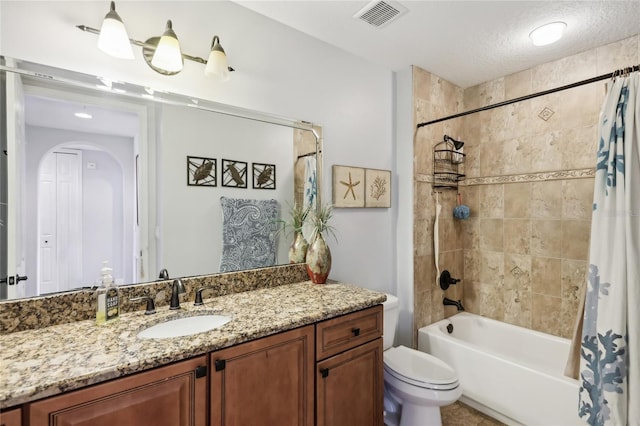 full bathroom with vanity, shower / bath combo with shower curtain, toilet, and a textured ceiling