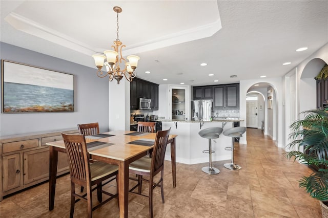 dining space featuring a tray ceiling and a chandelier