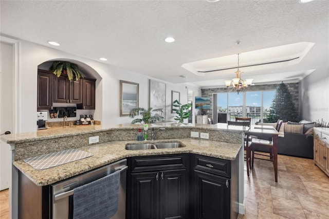 kitchen with pendant lighting, stainless steel dishwasher, a textured ceiling, a kitchen island with sink, and a chandelier