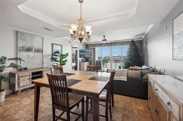 dining room with ceiling fan with notable chandelier, a tray ceiling, and a textured ceiling