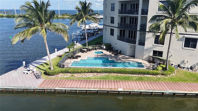 dock area featuring a balcony, a swimming pool with hot tub, a patio, and a water view