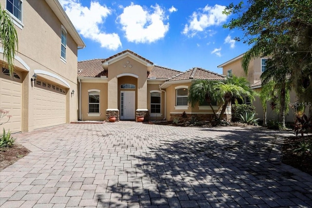 3757 Eagle Isle Cir, Kissimmee, FL 34746 - mediterranean / spanish-style house featuring stucco siding, a tile roof, a garage, and decorative driveway