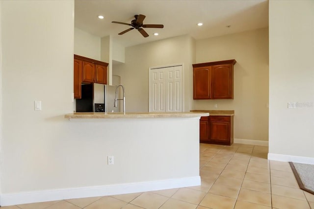 kitchen featuring ceiling fan, sink, light tile patterned floors, kitchen peninsula, and stainless steel refrigerator