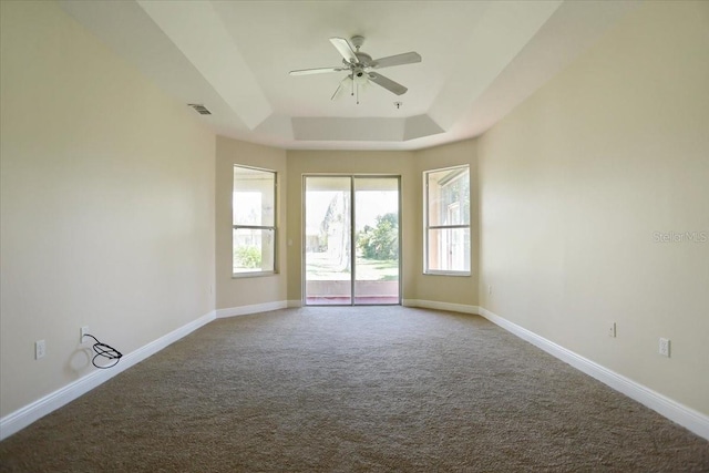 empty room featuring ceiling fan, a tray ceiling, and carpet flooring