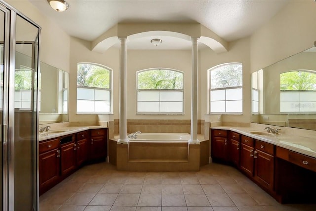 bathroom featuring lofted ceiling, tile patterned floors, a relaxing tiled tub, vanity, and ornate columns