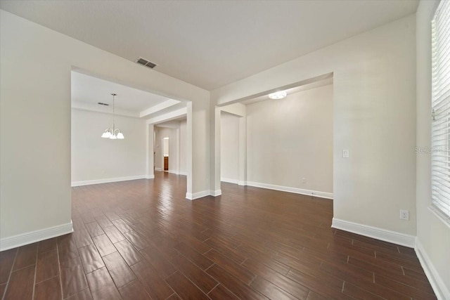 unfurnished room featuring a notable chandelier and dark hardwood / wood-style floors