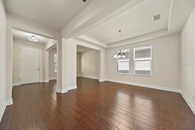 unfurnished room featuring a notable chandelier and dark hardwood / wood-style floors