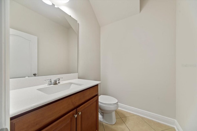 bathroom with tile patterned flooring, vaulted ceiling, vanity, and toilet