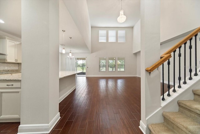 entryway with a towering ceiling, a chandelier, and dark hardwood / wood-style flooring